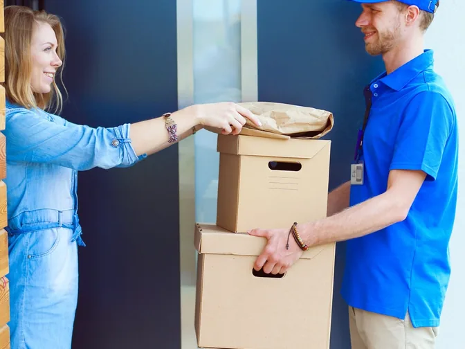 Un transportista recibe dos cajas en la puerta de una casa